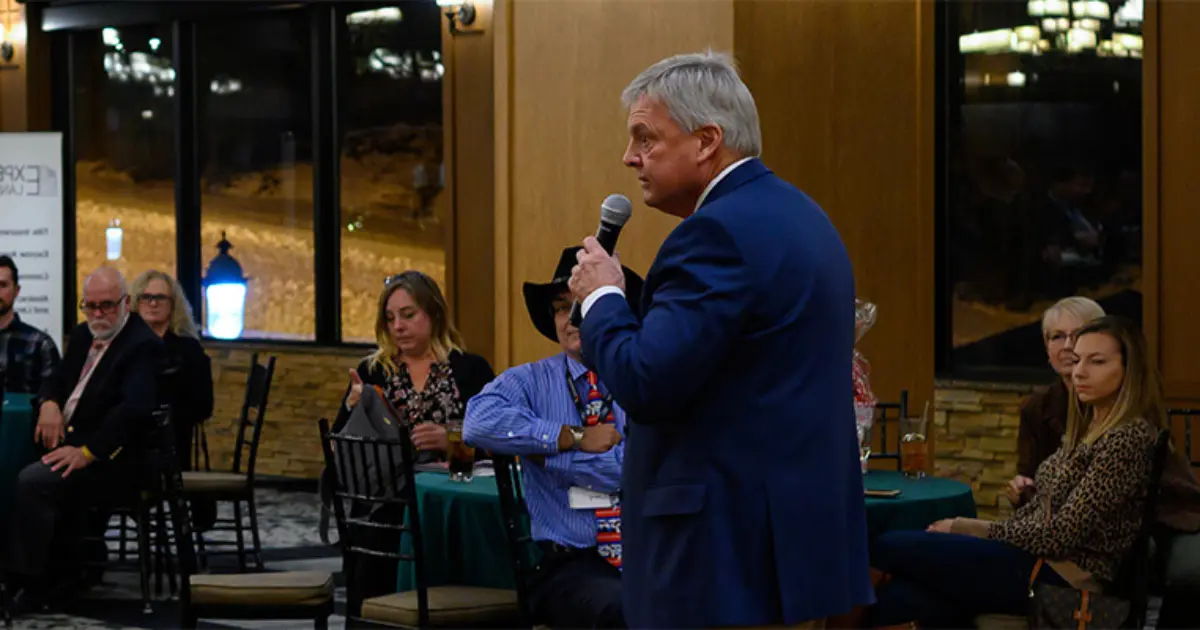 Richard Plinke at a lectern addressing an audience—Speaking page header.