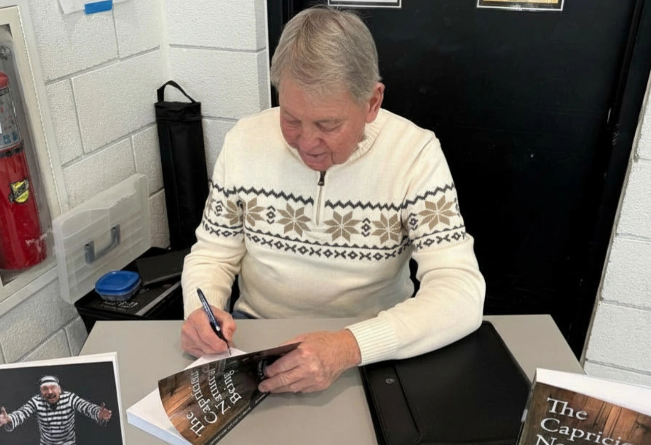 Author Richard Plinke signs a copy of The Capricious Nature of Being at a book signing event.
